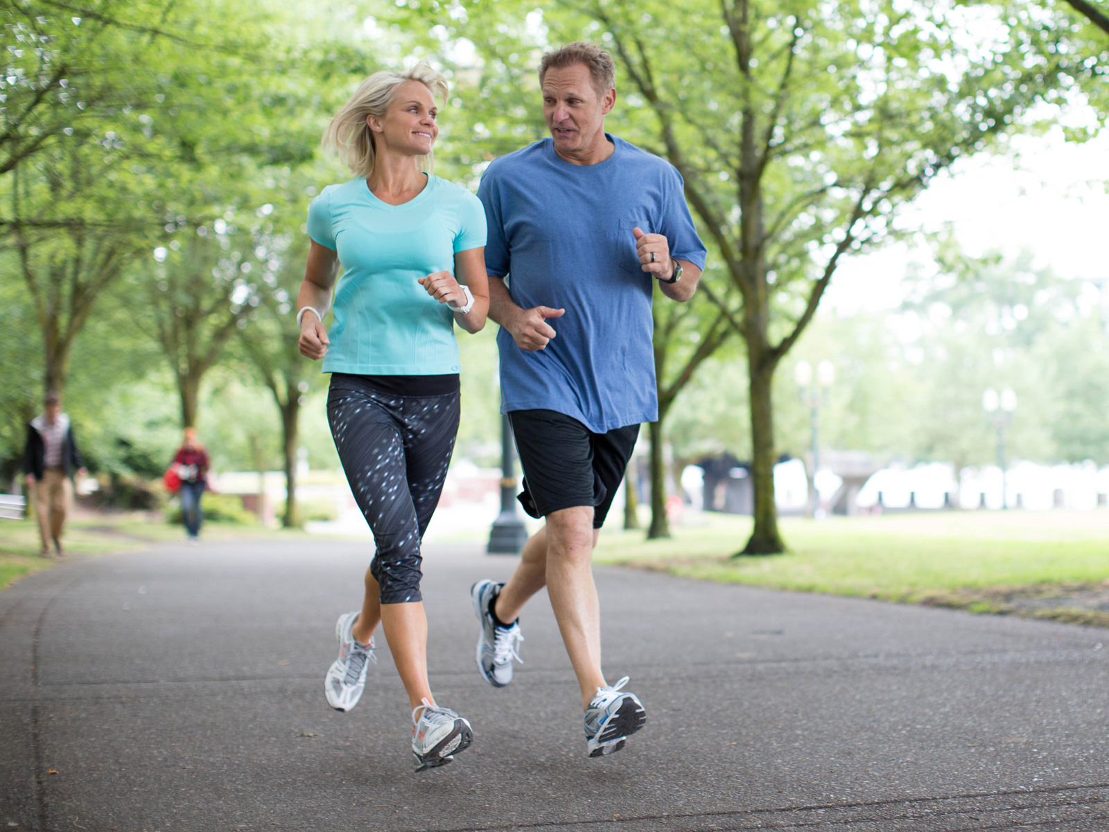 a man and woman enjoy jogging in the park while they wear activity trackers